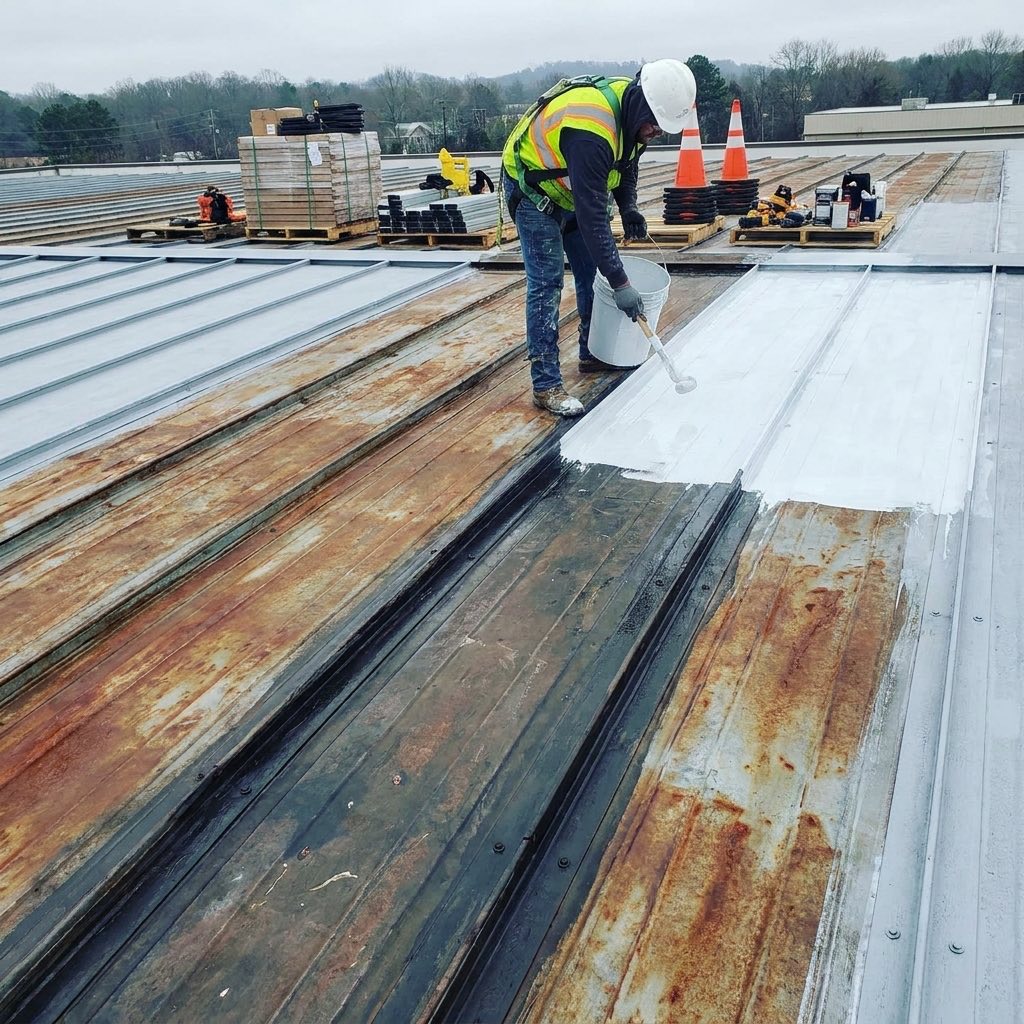 Commercial metal roof being restored with a protective white coating